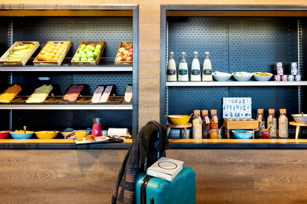 a suitcase sitting on a bench in front of a shelf of food at Moxy Edinburgh in Edinburgh