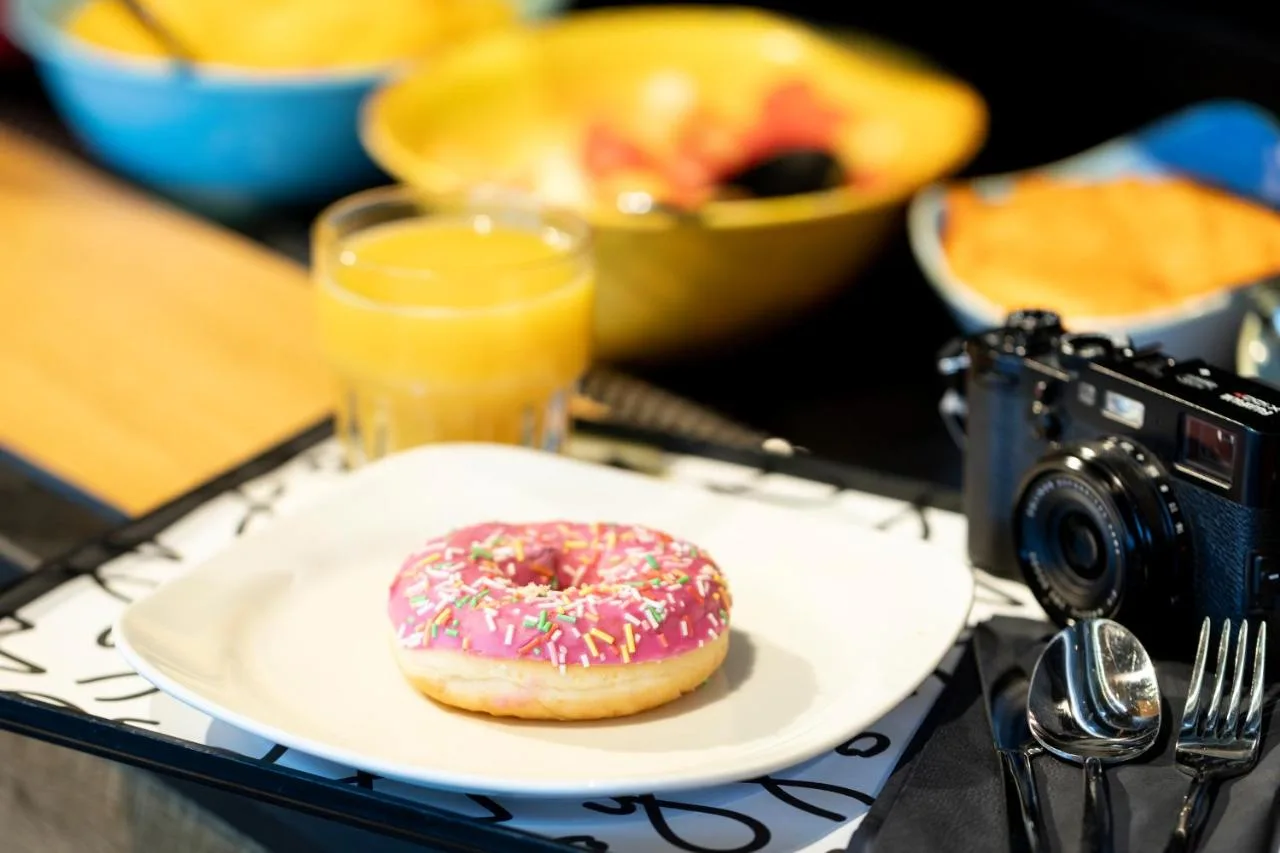 a donut on a plate on a table with a camera at Moxy Edinburgh in Edinburgh