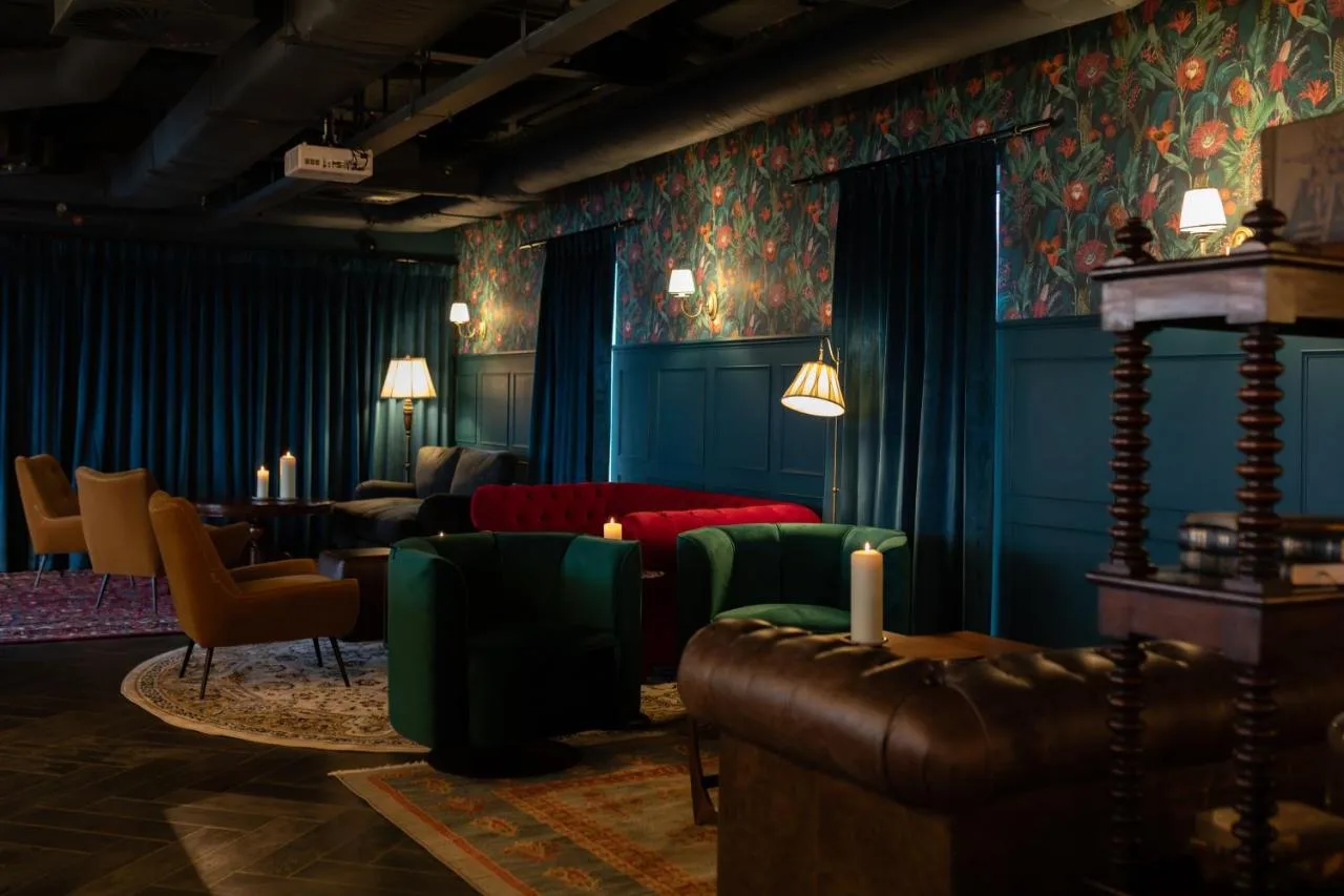 a living room with blue walls and green furniture at Moxy Edinburgh in Edinburgh