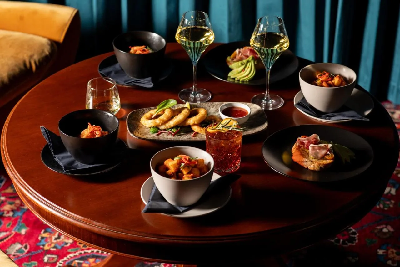 a table with plates of food and glasses of wine at Moxy Edinburgh in Edinburgh