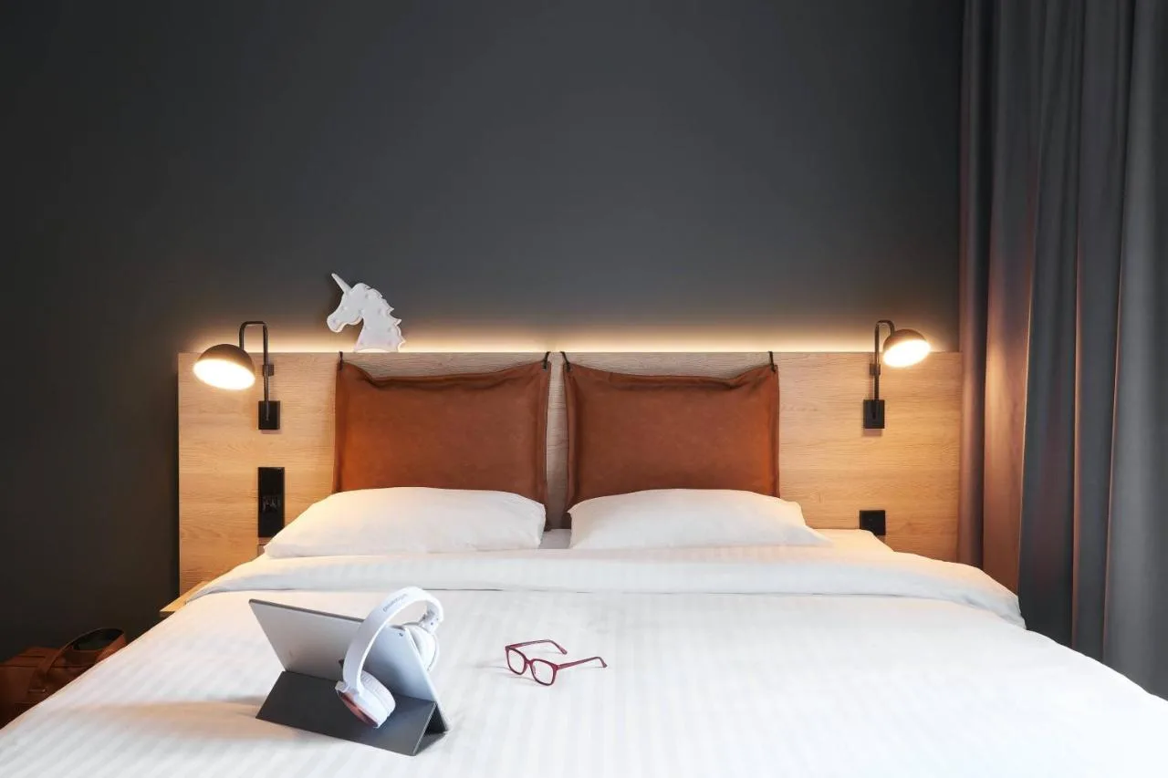 a bed with a laptop and a pair of shoes on it at Moxy Edinburgh in Edinburgh